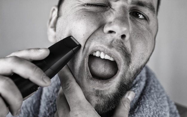 Monochrome textured portrait bearded man shaving electric