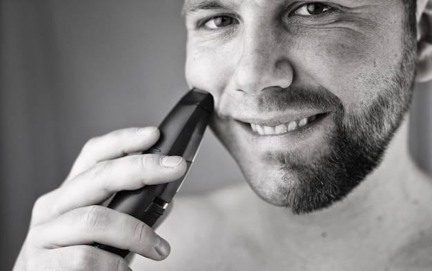 Monochrome textured portrait bearded man shaving electric