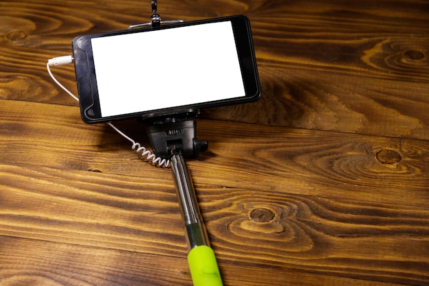 Foto monopod voor selfie met slimme telefoon op houten bureau. selfiestick met smartphone op houten ondergrond