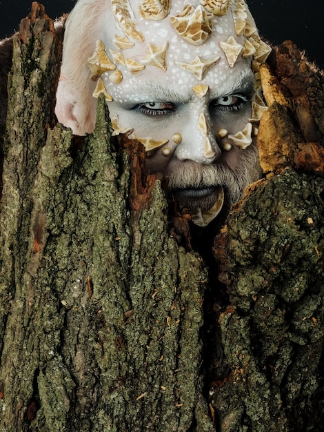 Photo monster with sharp thorns and warts man with dragon skin and bearded face druid behind old bark on b...