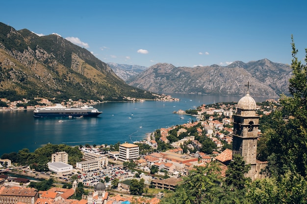 Montenegro adriatische zee en bergen. schilderachtig panorama van de stad kotor op een zomerse dag. panoramisch uitzicht over de baai van kotor en de stad. cruiseschip in de baai van kotor