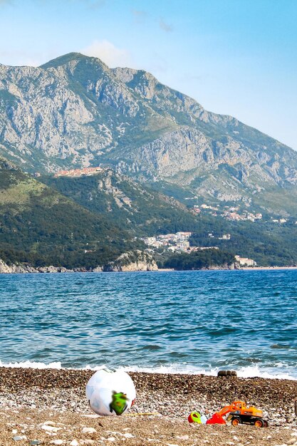 Foto montenegro becici beach i giocattoli per bambini giacciono sulla sabbia sullo sfondo del mare e delle montagne