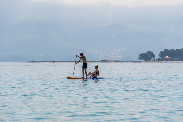 MONTENEGRO BUDVA. tourists are engaged in rowing on the board SUP on the surface of the calm sea