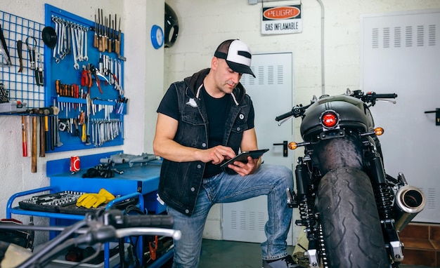 Monteur controleert aangepaste motorfiets met tablet