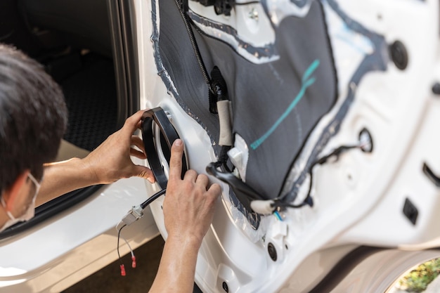 Monteur die luidspreker installeert op het portiergedeelte van het voertuig in de werkplaats in de garage