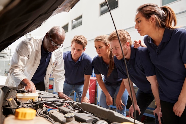 Monteur die stagiairs instrueert rond een lage hoek van een automotor