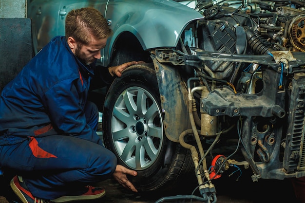 Monteur gerepareerde voertuigen op wielen. Mechanic Holding Car Tyre bij Garage.