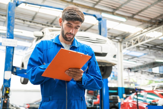 Monteur in blauwe werkkleding controleert de checklist voor voertuigonderhoud Autoreparatieservice