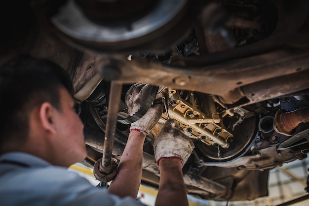 monteur is bezig met het controleren van de auto's die in het autoservicecentrum werken met een vorkheftruck. Autoreparatie en -onderhoud