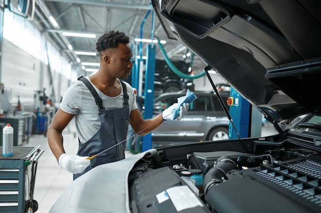 Foto monteur man controleert oliepeil in mechanische werkplaats