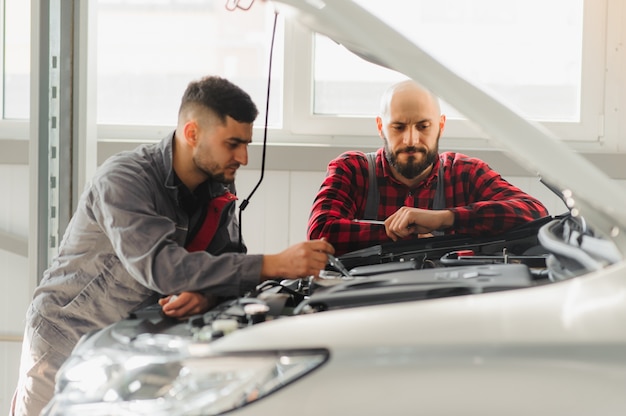Monteur mannen met moersleutel auto motor repareren in de werkplaats