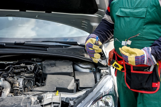 Monteur met lamp en kabels van koplamp van auto