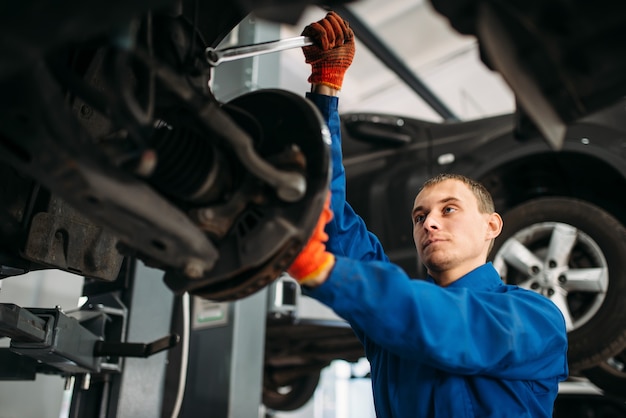 Monteur met moersleutel repareert de ophanging van de auto.