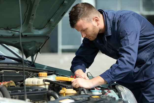 Monteur met scantool die auto diagnosticeert in open kap close-up