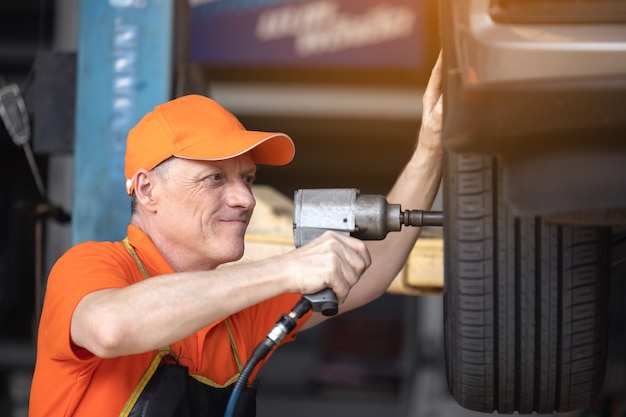 Monteur onderhoud autoband met slagpistool in garage van reparatie servicestation