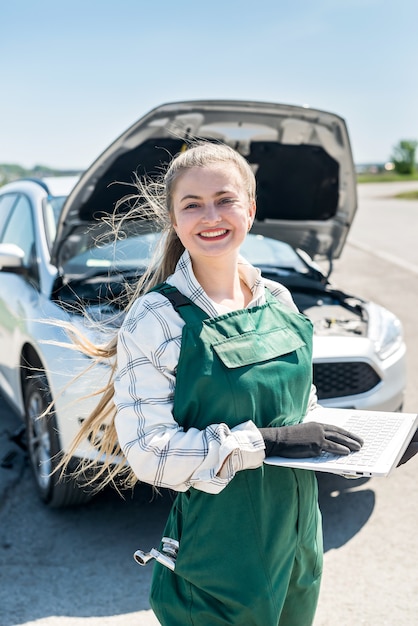 Monteur vrouw poseren met laptop voor kapotte auto