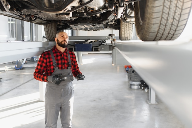 Monteur werkt onder auto bij de reparatie-garage