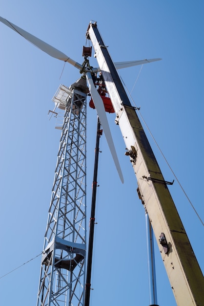 Foto monteurs gebruiken vrachtwagenkraan en hoogwerker om windturbinerotor te installeren