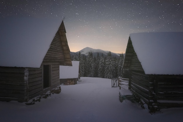 Moody winter landscape with wooden houses in snowy mountains