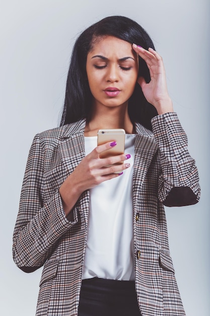 Mooi Afrikaans Amerikaans meisje houdt de telefoon in handen op een grijze achtergrond