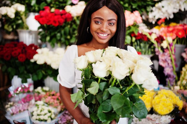 Mooi Afrikaans-Amerikaans meisje in een witte jurk met bloemen in handen