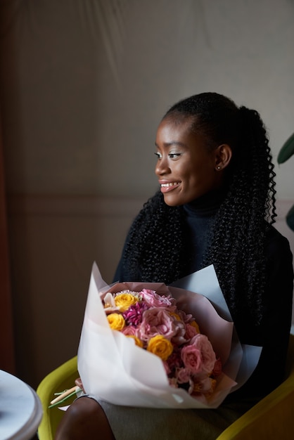 mooi Afrikaans Amerikaans meisje met een boeket bloemen op dating in een café