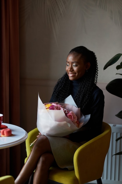 mooi Afrikaans Amerikaans meisje met een boeket bloemen op dating in een café