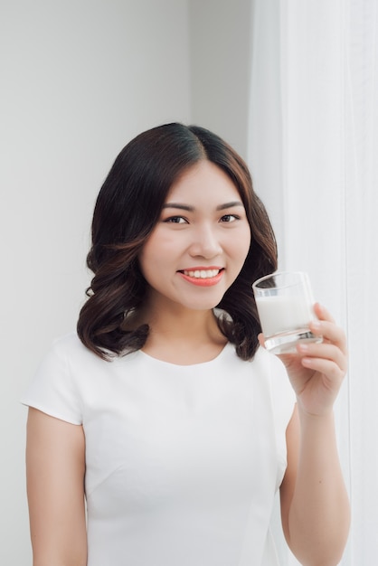 Mooi Aziatisch meisje dat een glas melk drinkt.
