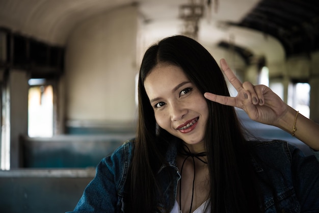 Mooi Aziatisch meisje poseert twee vingers op trein vintage stijllifestylehipster