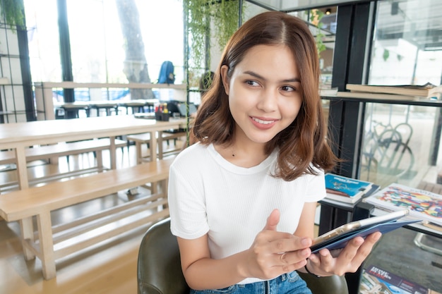 Mooi bedrijfsmeisje die met tablet, smartphone en het drinken koffie in koffiewinkel werken