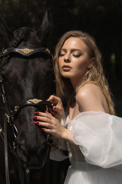 Foto mooi blank meisje in een trouwjurk naast een paard