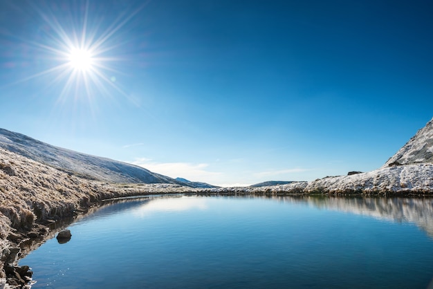 Mooi blauw meer in de bergen, de tijd van de ochtendzonsopgang. Landschap met sneeuw stralende zon