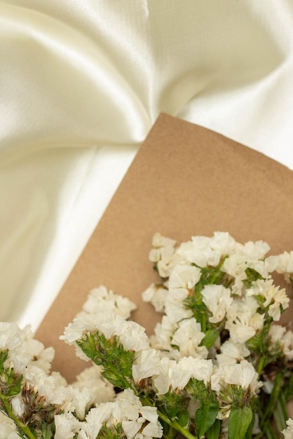 Mooi bloemconcept Boeket van wit bloeiende statice met bruin papier op witte doek