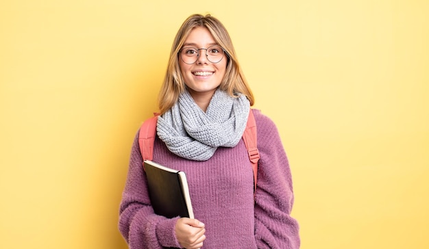 Mooi blond meisje dat er blij en aangenaam verrast uitziet. studentenconcept