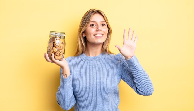 Mooi blond meisje dat lacht en er vriendelijk uitziet, met nummer vijf. zelfgemaakte koekjes concept