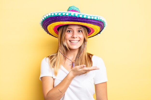 Mooi blond meisje dat vrolijk lacht, zich gelukkig voelt en een concept toont. mexicaanse hoed concept