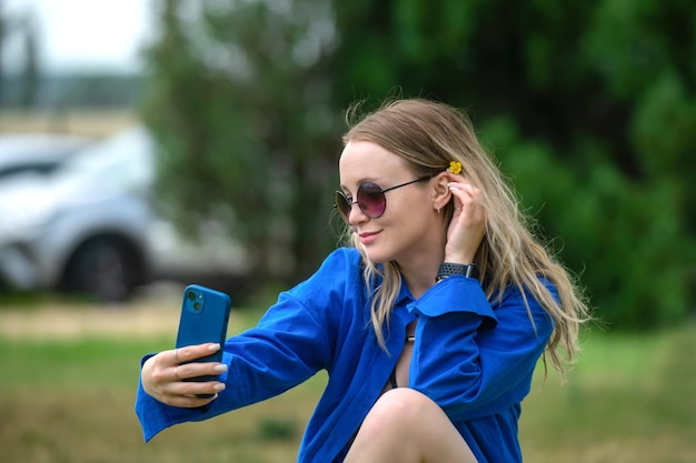 mooi blond meisje met golvend haar maakt een selfie aan de telefoon in de natuur