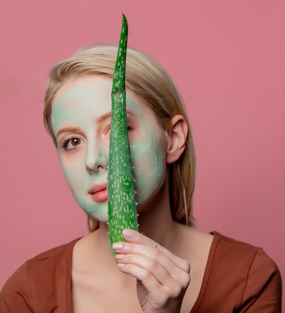 Mooi blond meisje met groen masker en aloëtak