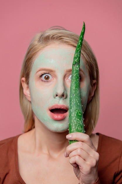 Mooi blond meisje met groen masker en aloëtak