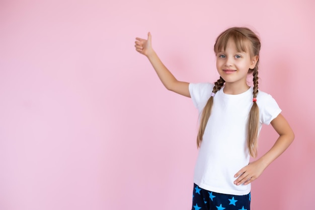 Mooi blond meisje met lang haar in wit T-shirt glimlachend op een roze achtergrond