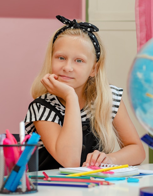 Mooi blond schoolmeisje dat thuis haar huiswerk doet. Studeren en leren