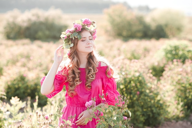 Mooi blond tienermeisje in roze jurk met roze bloem buitenshuis