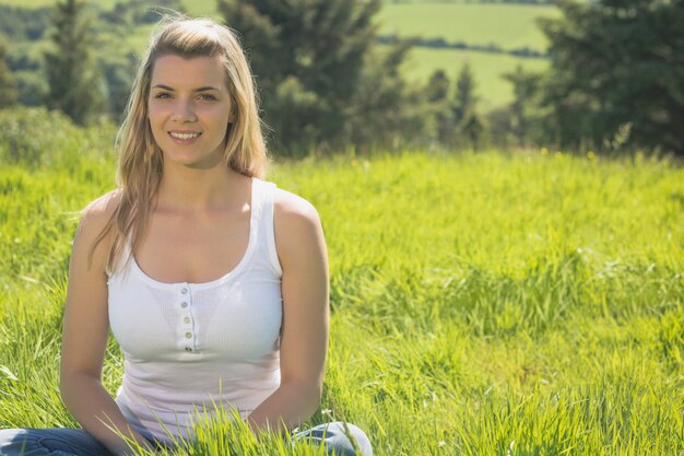 Mooi blonde die bij camerazitting op gras glimlachen