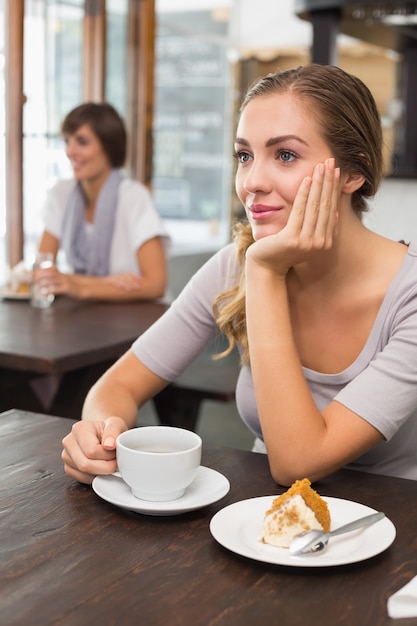 Mooi blonde die van cake en koffie genieten