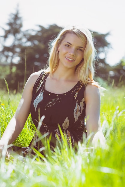 Mooi blonde in sundress zitting op gras