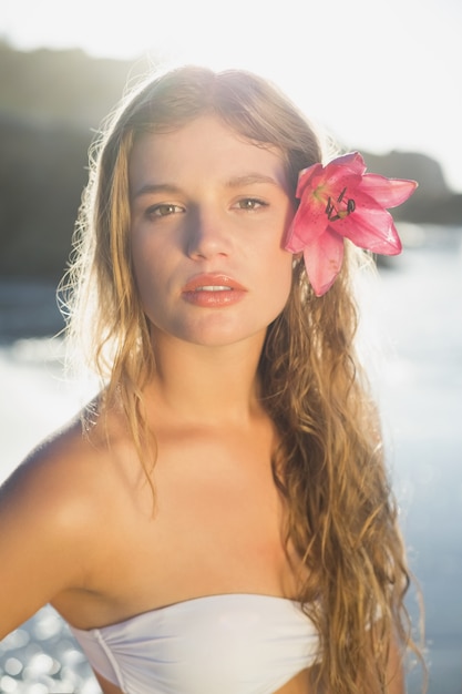 Mooi blonde met de toebehoren van het bloemhaar op het strand op een zonnige dag