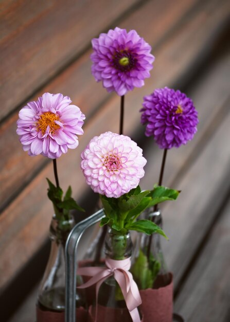 Foto mooi boeket rosa magenta roze violette dahliabloemen in glazen flessen op de tuinbank