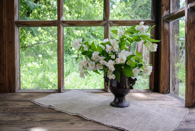 mooi boeket van jasmijn takken in een vaas bij een houten raam op het platteland