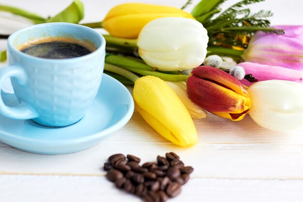 Mooi boeket van Lentebloemen op lichte houten oppervlak met kopje koffie in de ochtend