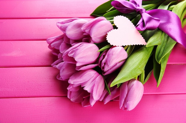 Mooi boeket van paarse tulpen op roze houten achtergrond